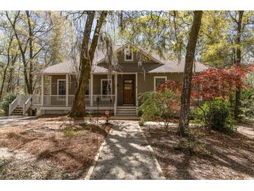 Charming single-story home with a welcoming front porch and beautiful landscaping, surrounded by mature trees at 53 Hope Ln., Pawleys Island, SC 29585