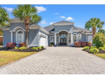 Stunning single-story home featuring a well-manicured lawn, brick driveway, and elegant architectural design at 8504 Juxa Dr., Myrtle Beach, SC 29579