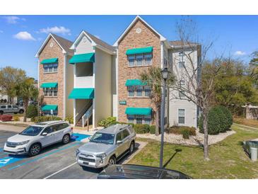 Condominium building featuring stone and siding with vibrant green awnings offering covered staircase and designated parking at 9764 Leyland Dr. # 9764 - 5, Myrtle Beach, SC 29572