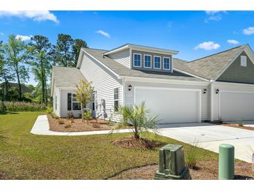 Charming home with a two-car garage, manicured lawn, and a walkway leading to the front door at 216 Kinross Ct., Little River, SC 29566