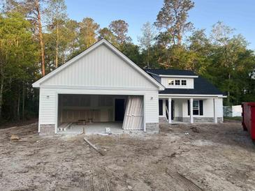 A charming new home shows white siding, a black roof, stone accents, and an attached two-car garage at 1274 Pinetucky Dr., Galivants Ferry, SC 29544