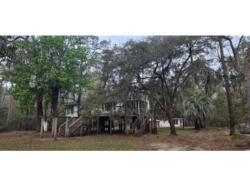 Exterior view of elevated home with surrounding lush trees and established landscaping at 1030 Waccamaw Lake Dr., Conway, SC 29526