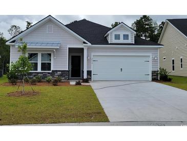 Charming single-Gathering home featuring a two-car garage, stone accents, manicured lawn, and modern architectural details at 2030 Lone Cypress Dr, Myrtle Beach, SC 29579