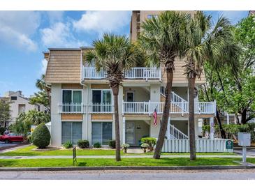 Inviting condo featuring white balconies and stairs accented by mature palm trees and well-maintained landscaping at 211 76Th Ave. N # A-2, Myrtle Beach, SC 29572
