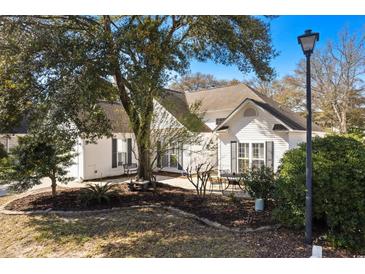 Charming home exterior with well-maintained landscaping, mature trees, and outdoor seating area at 808 Arbor Ln., North Myrtle Beach, SC 29582