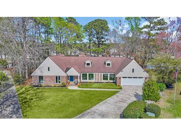 Charming home featuring a well-manicured lawn and a brick facade, complemented by a bright blue front door at 1625 Deer Park Ln., Surfside Beach, SC 29575
