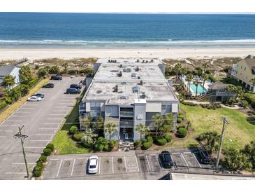 Aerial view of a beachfront complex with a pool and parking area, offering easy access to the sandy beach at 1501 S Waccamaw Dr. # 3-L, Murrells Inlet, SC 29576