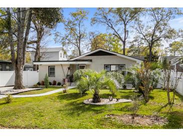 Charming one-story home with a landscaped yard, featuring a brick facade and mature trees at 613 Cypress Dr., Surfside Beach, SC 29575