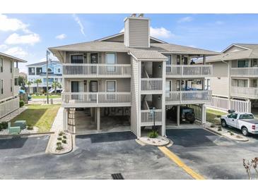 A three story condo building with a light grey exterior, multiple balconies, and parking underneath the units at 1801 N Ocean Blvd. # O-4, North Myrtle Beach, SC 29582