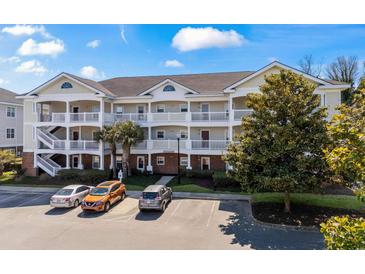 Three-story condo building with white railings, exterior stairs, and a well-maintained parking lot and landscaping at 5751 Oyster Catcher Dr. # 234, North Myrtle Beach, SC 29582