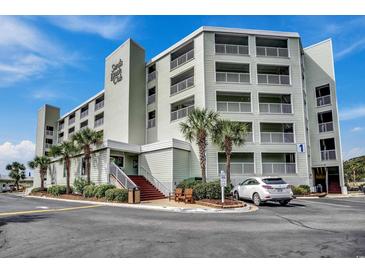 Sands Beach Club boasts light green siding, multiple balconies, and lush palm trees surrounding its entrance at 9400 Shore Dr. # 506, Myrtle Beach, SC 29572