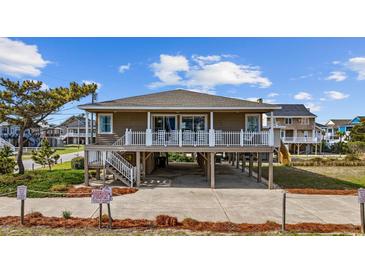Two-story beach house with a large deck and covered parking underneath the house, inviting coastal charm at 202 56Th Ave. N, North Myrtle Beach, SC 29582