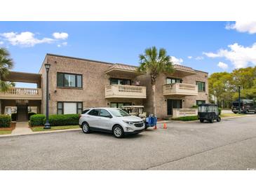 A two-story brick condo building featuring a palm tree and parked golf carts at 10100 Lakeshore Dr. # C-1, Myrtle Beach, SC 29572