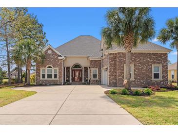 Beautiful brick home featuring a large driveway, manicured lawn, and mature palm trees offering great curb appeal at 2039 Woodburn Dr., Myrtle Beach, SC 29579
