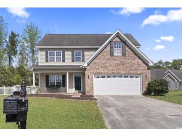 Charming two-story home featuring a brick accent, an attached garage and a well manicured lawn at 211 Oak Landing Dr., Conway, SC 29527