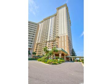 Stunning high-rise condo building boasts beautiful landscaping and inviting entrance on a sunny day at 9994 Beach Club Dr. # 408, Myrtle Beach, SC 29572