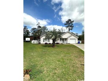 Charming single-story home with well-maintained lawn, mature palm tree, and a driveway leading to an attached garage at 1014 Mimosa Ct., Conway, SC 29527