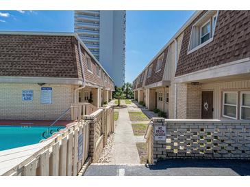 View of the building exterior with brick accents, manicured grounds, and a visible pool area at 5508 Porcher Dr. # 3, Myrtle Beach, SC 29577