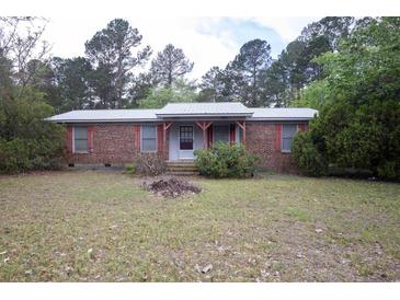 Charming single-story brick home featuring a metal roof, red trim, and a cozy front porch entrance at 1001 Creel St., Conway, SC 29527