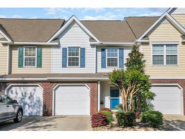 Charming townhome featuring brick accents, a one-car garage, and a blue front door surrounded by mature landscaping at 1098 Stanton Pl., Myrtle Beach, SC 29579