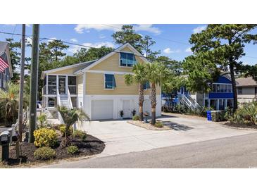 Charming yellow home with blue shutters, a two-car garage, and lush landscaping in a desirable community at 1114 S Dogwood Dr., Surfside Beach, SC 29575