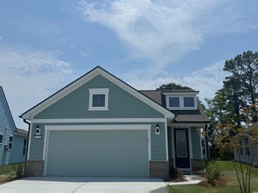 Charming home with a two-car garage, blue siding, brick detail and a manicured lawn at 1233 Lady Bird Way, North Myrtle Beach, SC 29582