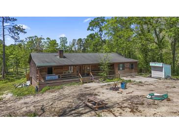 Charming cabin-style home featuring a cozy front porch and rustic wood siding surrounded by lush greenery at 1651 Weldon Ln., Conway, SC 29526