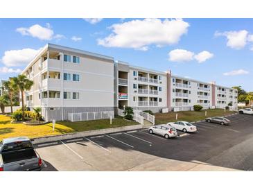 Four-story condo building with white exterior, multiple balconies, parking lot, and palm trees at 191 Maison Dr. # B-319, Myrtle Beach, SC 29572