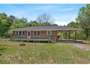 Charming brick home featuring a wooden deck, convenient carport, and lush green surroundings at 2865 N Nichols Hwy., Nichols, SC 29581