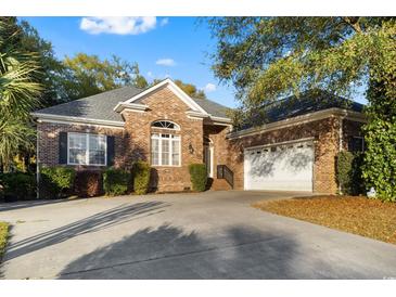 Charming single-Gathering brick home featuring a well-maintained lawn and a spacious driveway leading to a two-car garage at 808 East Coast Ln., North Myrtle Beach, SC 29582