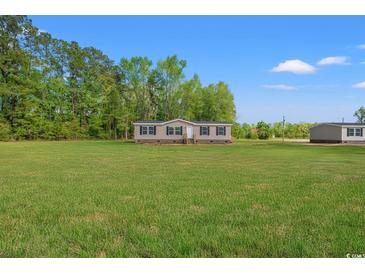 A charming single story house with a lush green lawn and a backdrop of mature trees on a sunny day at 814 S Midway Hwy., Johnsonville, SC 29555