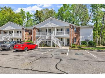 Inviting two-story condo with white trim, brick accents, outdoor stairs, and ample parking surrounded by lush trees at 157 Egret Run Ln. # 514, Pawleys Island, SC 29585
