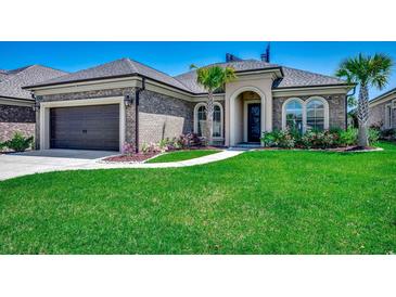 Charming brick home with a well-manicured lawn, beautiful landscaping, and an attached two-car garage at 311 Las Olas Dr., Myrtle Beach, SC 29577