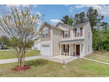 Charming two-story home featuring a covered entryway, attached garage, and well-maintained landscaping at 113 Winding Path Dr., Loris, SC 29569