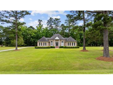 Charming one-story brick home featuring a manicured lawn, lush landscaping, and a symmetrical facade at 4100 Hagwood Circle, Conway, SC 29526