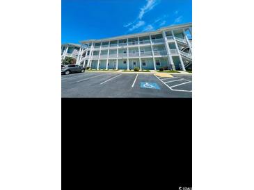 Exterior view of the building with a parking lot, blue sky, white balconies and stairs on the side of the property at 4669 Wild Iris Dr. # 22-2O2, Myrtle Beach, SC 29577