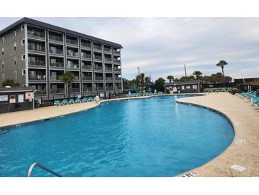 A large pool with a condo building in the background and several lounge chairs on the pool deck at 5905 S Kings Hwy. # 404 A, Myrtle Beach, SC 29575