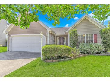 Charming home featuring manicured lawn, lush shrubs, and a welcoming two-car garage at 6000 Isabel Ct., Myrtle Beach, SC 29579