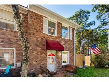 Charming brick townhome featuring an American flag, inviting entrance with a red awning and decorated door at 707 S 26Th Ave. S # L, North Myrtle Beach, SC 29582