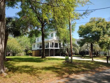 Inviting elevated coastal home featuring a spacious front porch and lush green landscaping at 69 Sea Level Loop, Pawleys Island, SC 29585