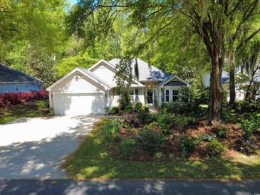 Charming home featuring an attached garage, complemented by lush landscaping and mature trees at 64 Reef Run Rd., Pawleys Island, SC 29585