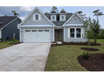 Charming home featuring a pristine two-car garage, fresh landscaping, and stylish architectural details at 712 Lapwind Loop, Myrtle Beach, SC 29579