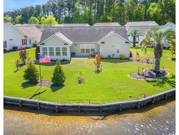 Well-manicured backyard with lush lawn, waterfront view, and mature trees at 1154 Lampwick Ln., Murrells Inlet, SC 29576