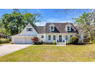 Charming home with a white exterior, dormers, lush landscaping, and attached garage at 129 Old Cedar Loop, Pawleys Island, SC 29585