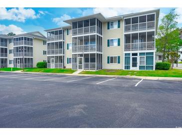 Attractive condominium building with screened porches and ample parking on a sunny day at 202 Landing Rd. # B, North Myrtle Beach, SC 29582