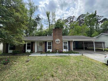 Charming brick home with a carport and a beautifully landscaped front yard with a brick chimney at 342 Red Fox Rd., Myrtle Beach, SC 29579