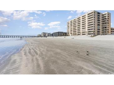 Expansive beach view with a fishing pier and condo buildings in the background on a sunny day with puffy clouds at 6100 N Ocean Blvd. # 804, North Myrtle Beach, SC 29582