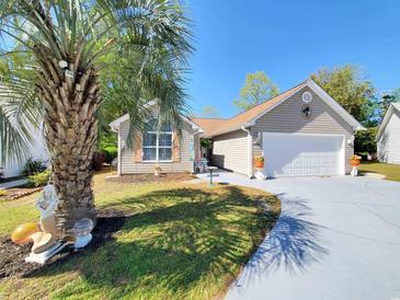 Charming single-story home with a well-manicured lawn, a two-car garage, and beautiful palm tree in the front yard at 2488 Oriole Dr., Murrells Inlet, SC 29576