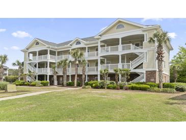 Beautiful condo building with white balconies, palm trees, and manicured lawn at 5801 Oyster Catcher Dr. # 912, North Myrtle Beach, SC 29582