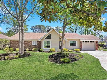 Charming single-story home with a well-manicured lawn and mature trees at 584 Circle Dr., Surfside Beach, SC 29575